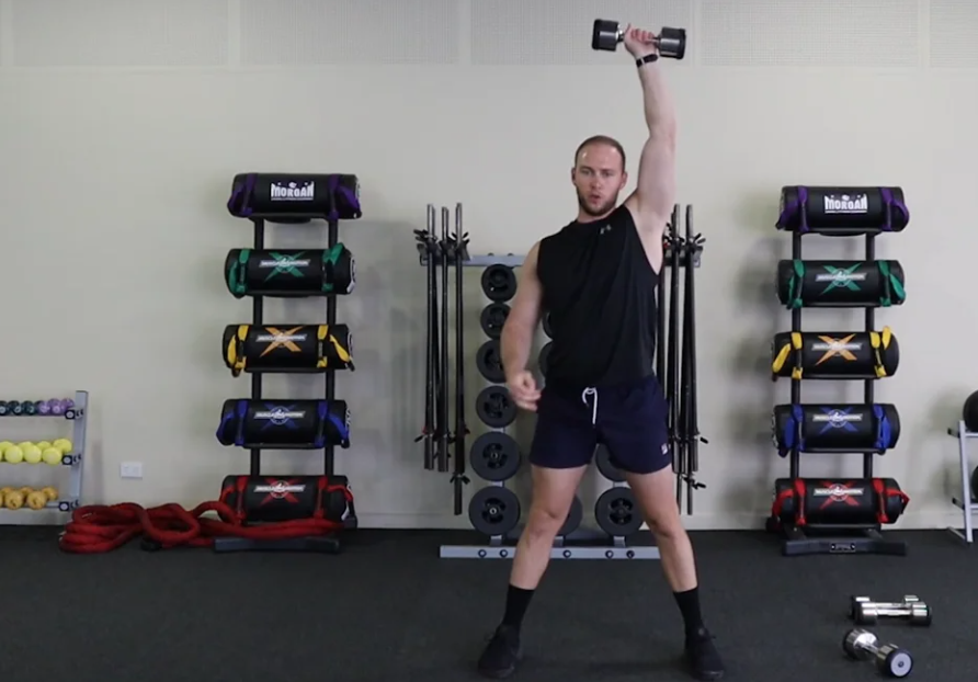 Gym Instructor Olly lifting dumbbells above his head doing exercise