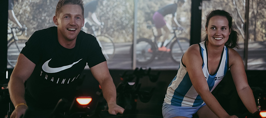 Two spinners riding the new spin bikes while smiling