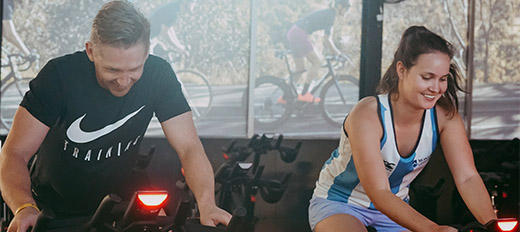 Women and man on spin bikes smiling