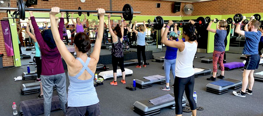 A Body Pump class in a group exercise room at Collingwood Leisure Centre lifting weights above their heads