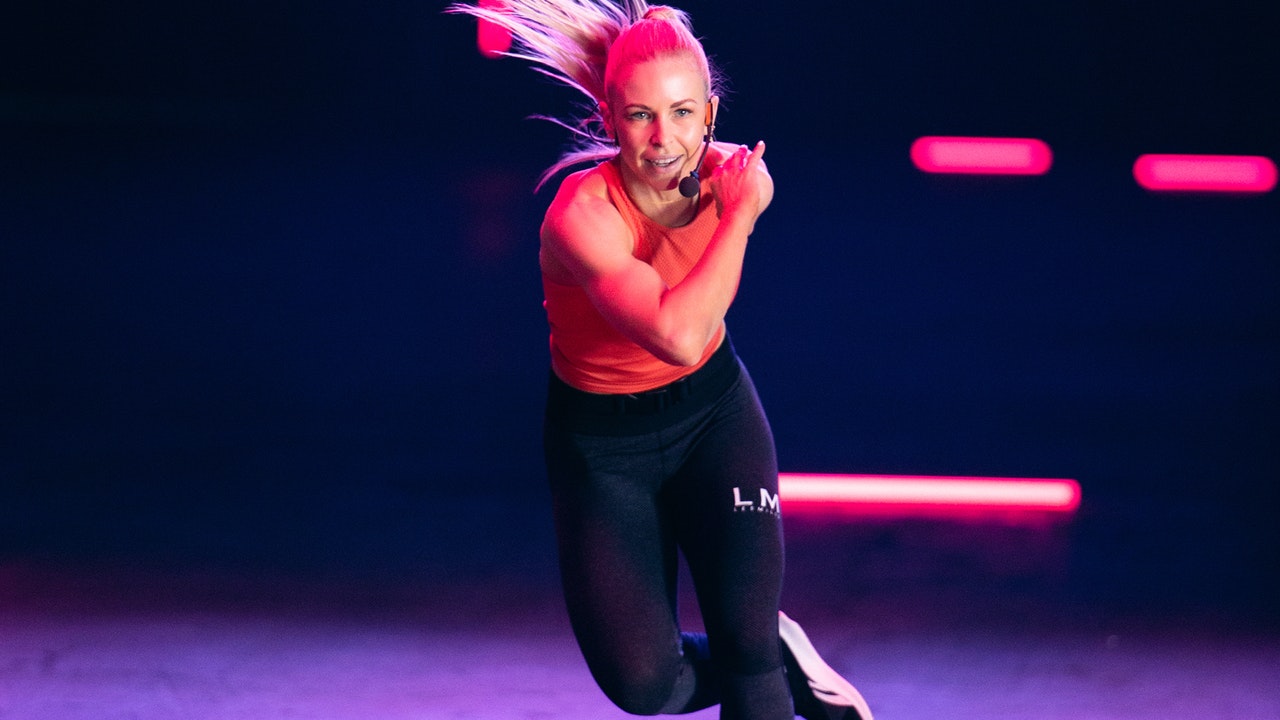 A fit blonde woman doing exercise with LED lights in the background