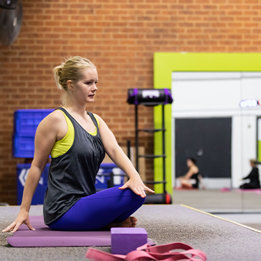 A pilates instructor on stage in Collingwood group exercise room