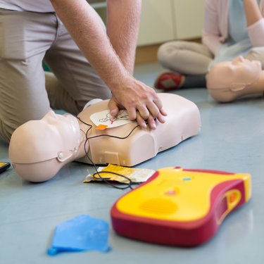 Close up of a person learning CPR and defibrillation on a dummy