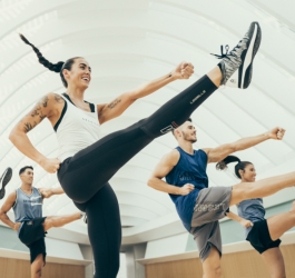 A group of people in a group exercise class kicking their right leg up in the air