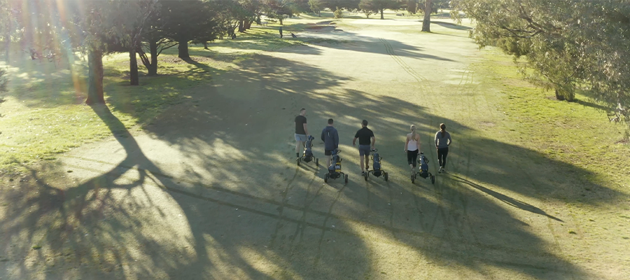 A group of golfers walking down the fairway in the morning