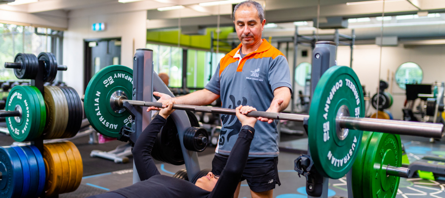A Gym Instructor assisting a customer on weight equipment in the Collingwood gym