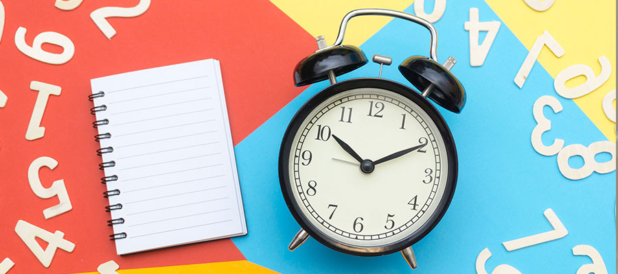 A clock and a notepad with number surround it on a colourful bench