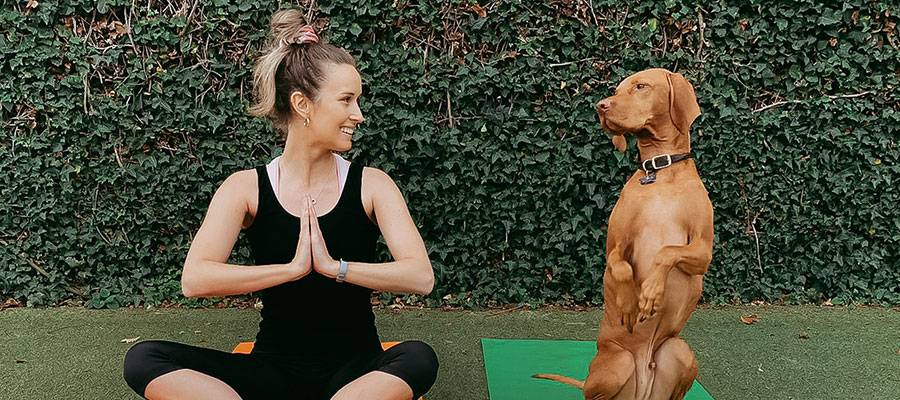 A girl and her dog sitting on yoga mats doing yoga at home