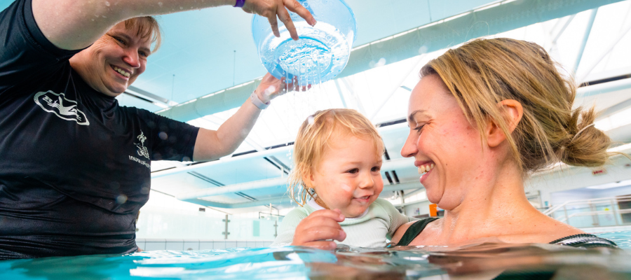Robyn in a child swimming lesson with a young child and mother