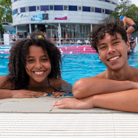 Two young adults in Fitzroy Pool leaning on wetdeck smiling at camera