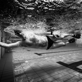 A man touching wall for tumble-turn underwater in a pool