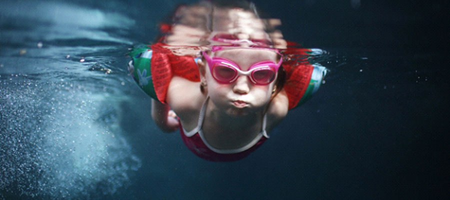 A young girl with floaties on swimming underwater