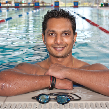 Man smiling at the camera at the edge of a pool