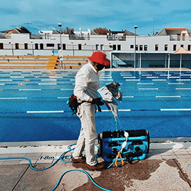 Staff member cleaning Fitzroy Swimming Pool wearing a mask