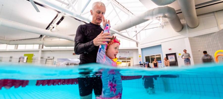 A swim instructor teaching a young girl a swimming position in Collingwood pool
