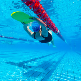 Woman swimming backstroke with kickboard underwater