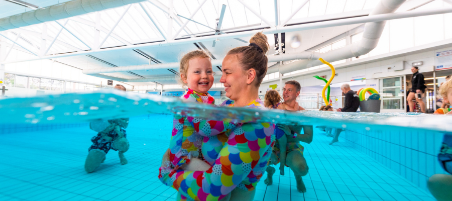 A young girl and her mother in a learn to swim class at Collingwood smiling at each other