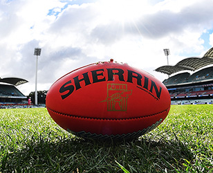 Red sherrin football sitting on an oval