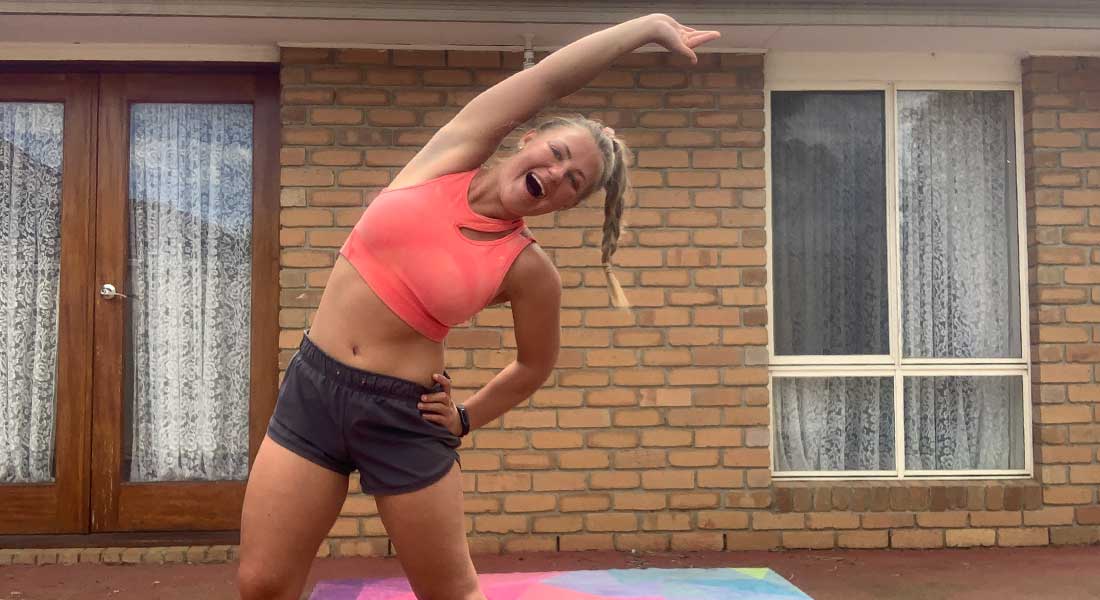 Gym Instructor Mel in her active wear standing in her back garden on her colourful gym mat and smiling