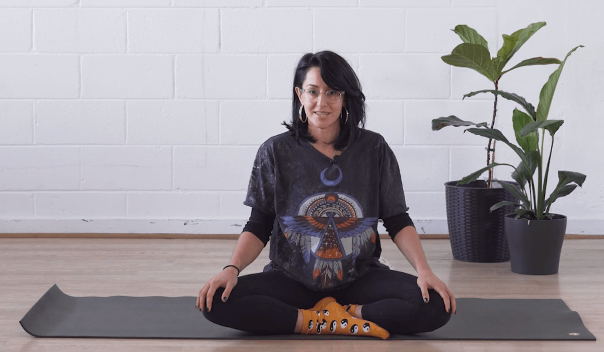 Instructor Alissia sitting cross legged on a yoga mat smiling