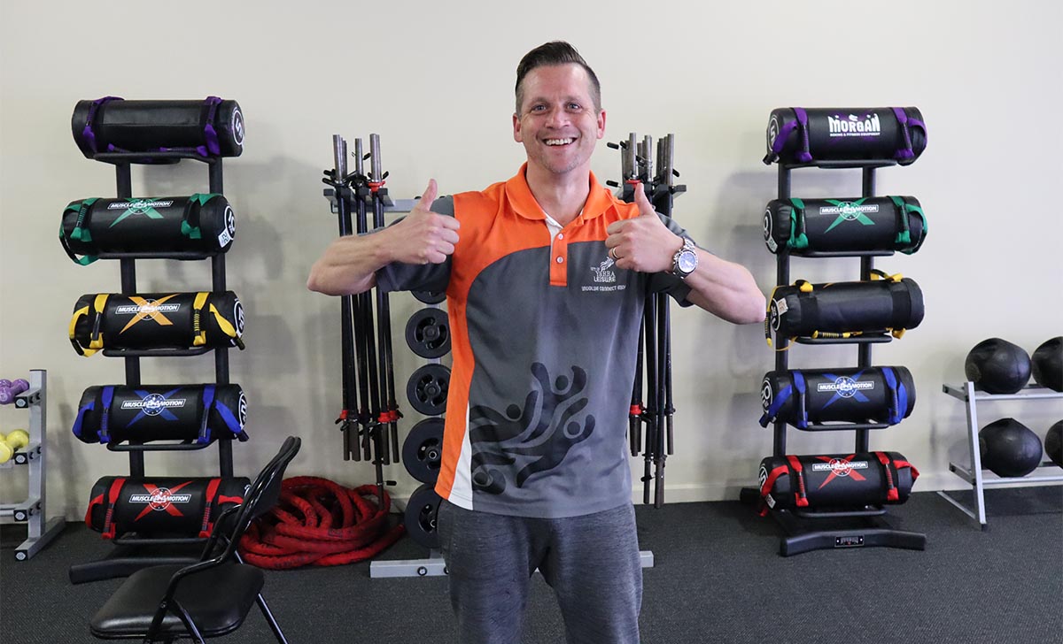 Gym Instructor Andrew standing in the gym with his thumbs up and smiling