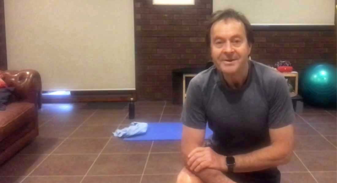 Gym Instructor Bill kneeling down in his house and smiling