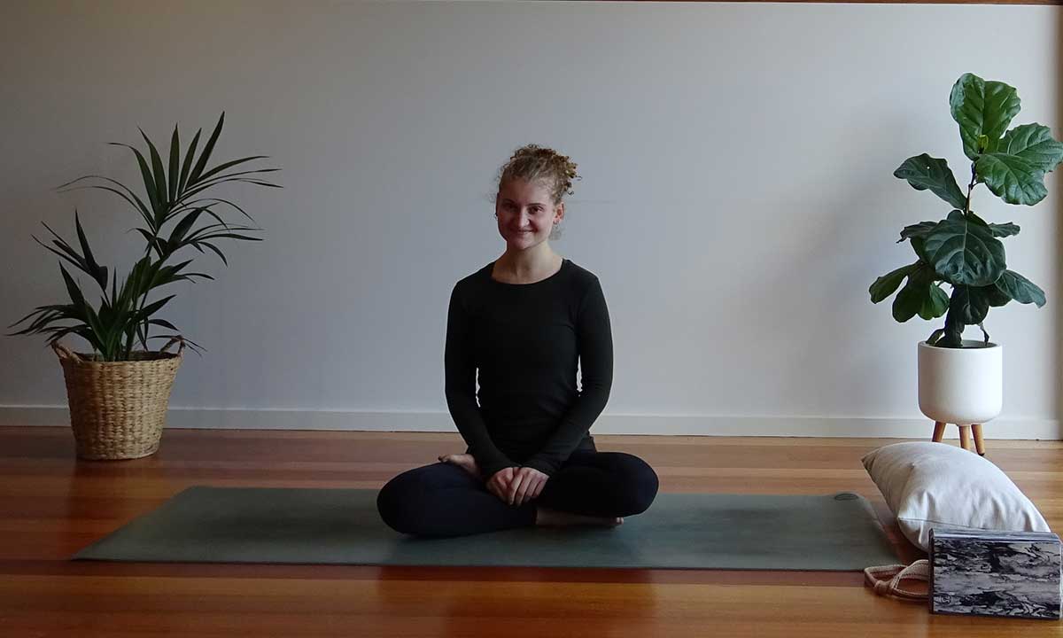 Yarra Leisure group exercise instructor Caragh sitting on a yoga mat and smiling