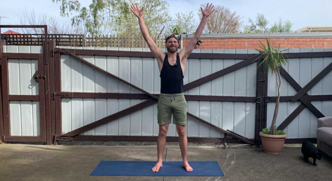 Gym Instructor Leigh standing in has backyard with his hands up and smiling