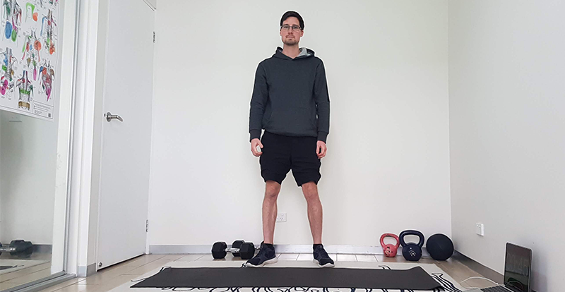 Gym Instructor Adam standing in a room at home standing on a yoga mat smiling
