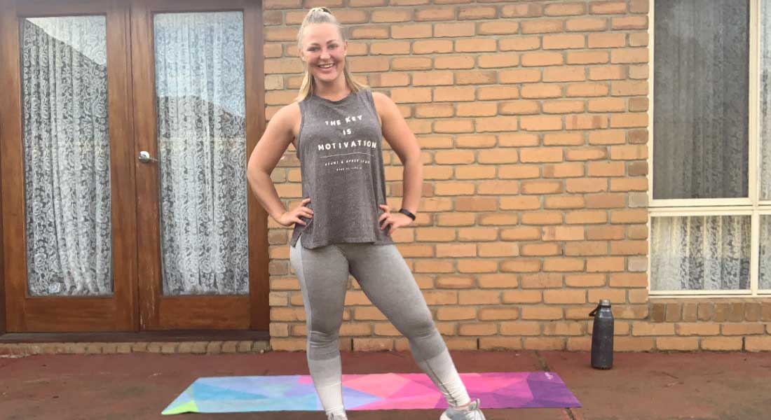Gym Instructor Mel standing in front of her house in her backyard smiling