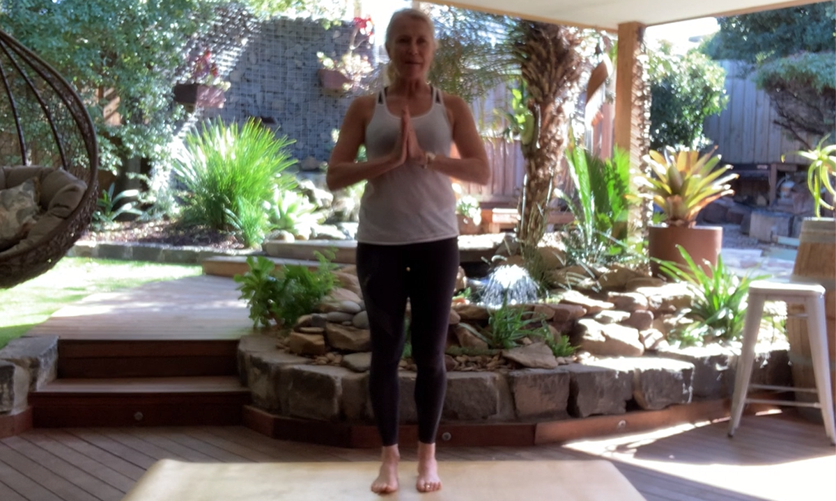 Gym Instructor Lisa standing with her hands together in her lovely backyard