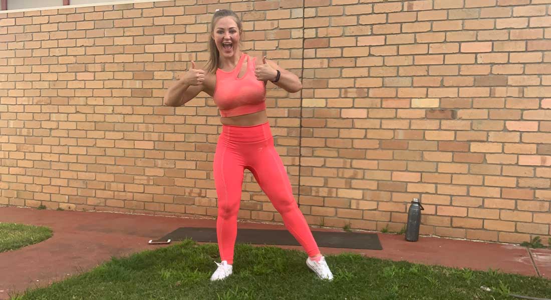 Gym Instructor Mel in her active wear standing in her back garden smiling with her thumbs up