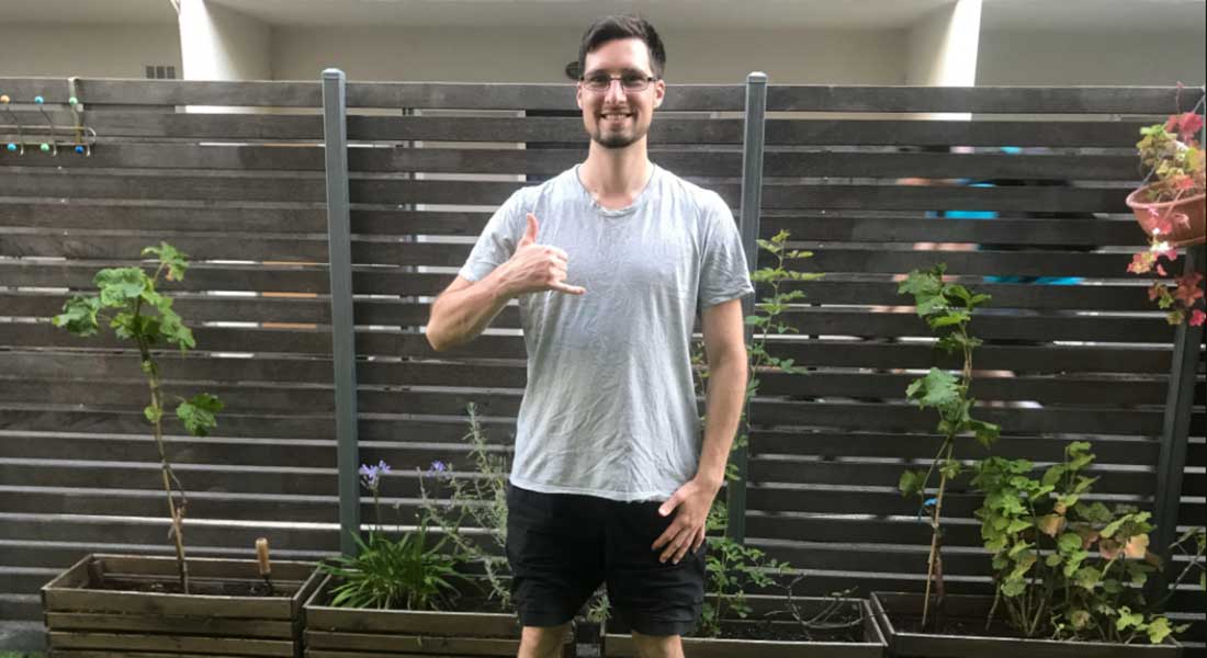 Gym Instructor Adam standing in his backyard smiling with his thumb up