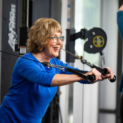 Older woman working out on dual pulley cable machine